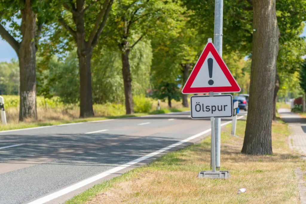 Warnschild "Ölspur" am Straßenrand